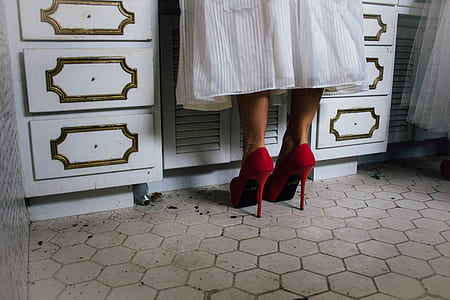 person in white skirt wearing pair of red stilettos