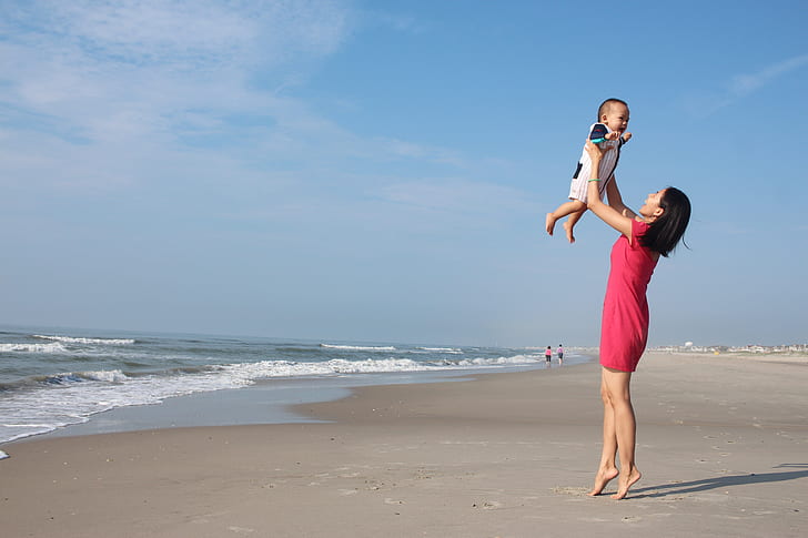 woman raising child near seashore