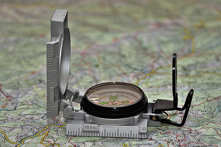round black and gray analog compass on green map