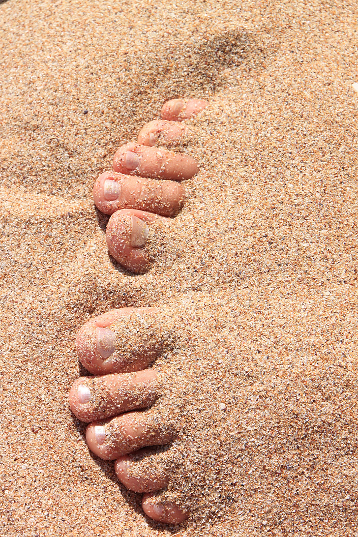 human foot under brown sand