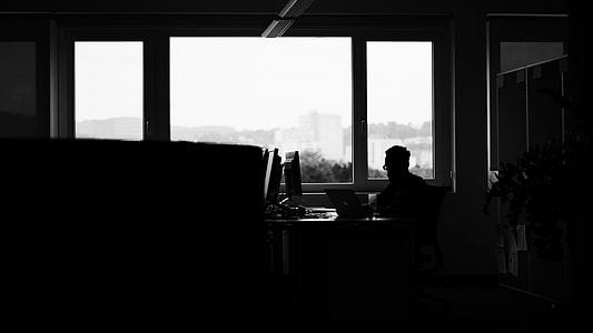 photo of man on black desk using laptop