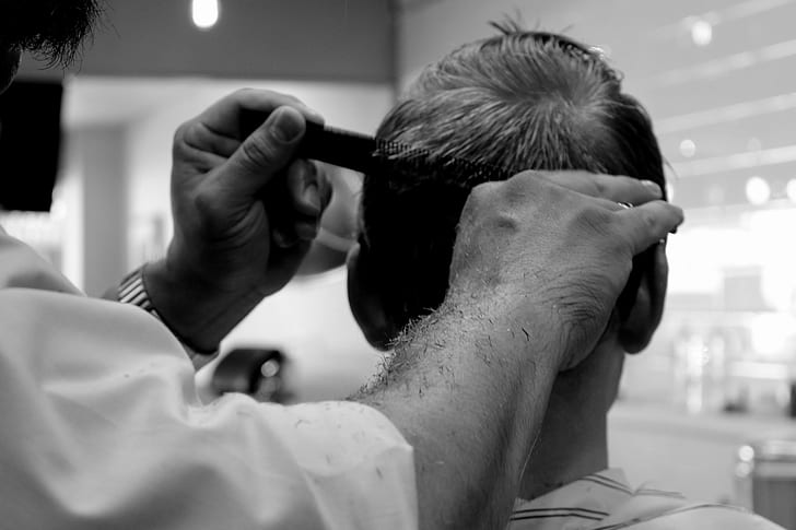 grayscale photography of barber cutting hair