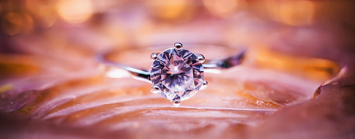 selective focus photography of silver ring with round-cut diamond gemstone