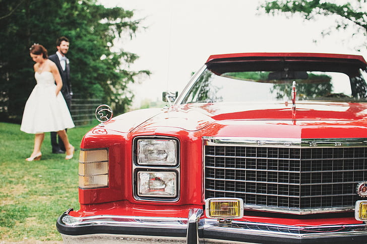 red car in front of bride and groom