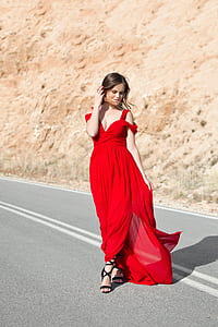 woman wearing red tank dress standing at asphalt road