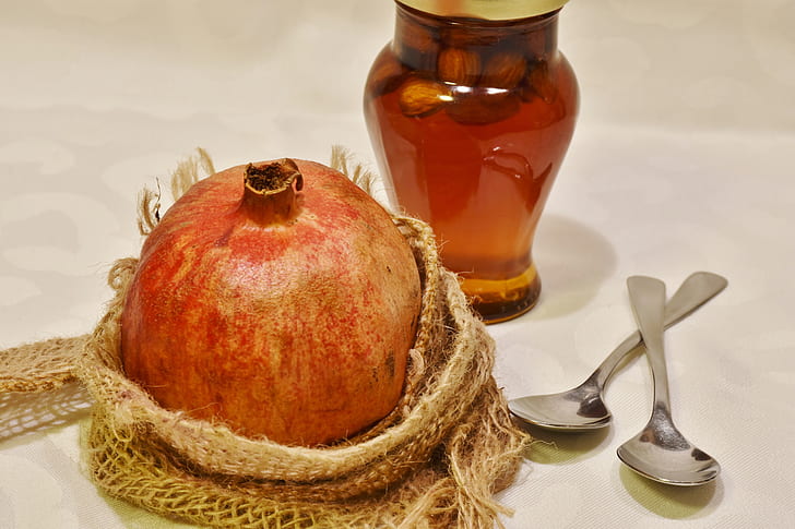 promegranate fruit beside amber glass bottle and two gray teaspoons