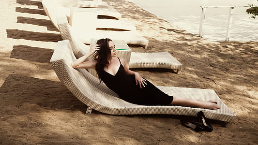 woman in black spaghetti strap dress on beige beach lounge chair