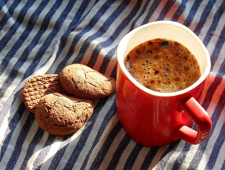 coffee in red and white ceramic mug near three cookies