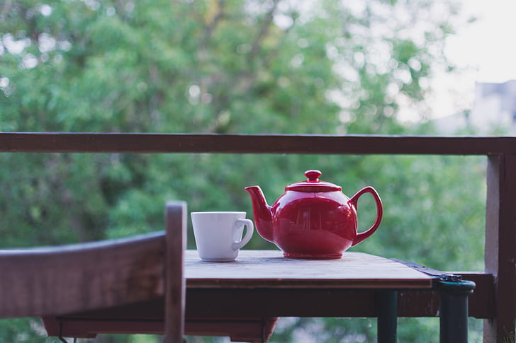 red ceramic teapot near white ceramic mug on brown wooden table