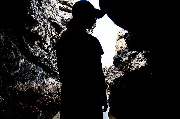 silhouette photography of person inside a cave during daytime