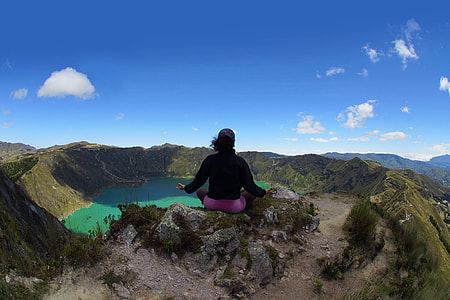woman meditating on top of mountain during daytime