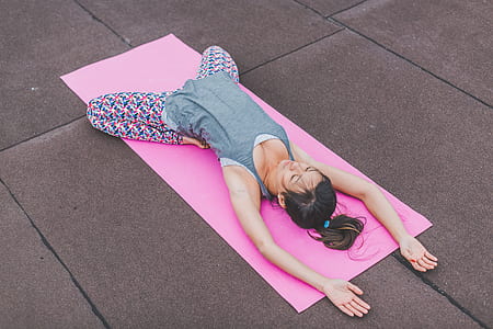 woman wearing gray sleeveless top and multicolored leggings doing yoga