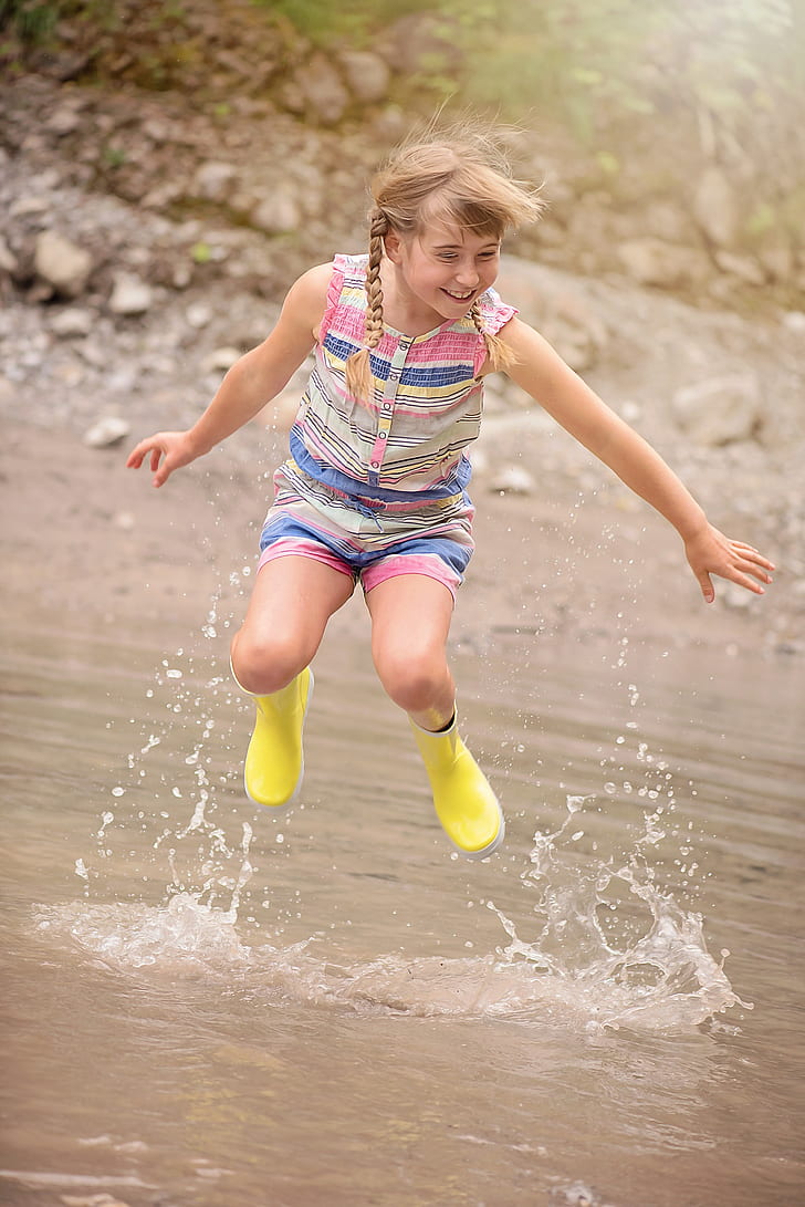 jumping brown haired girl on body of water