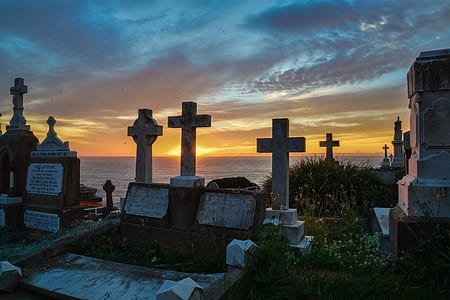 cemetery by the sea under blue and orange sky during sunset