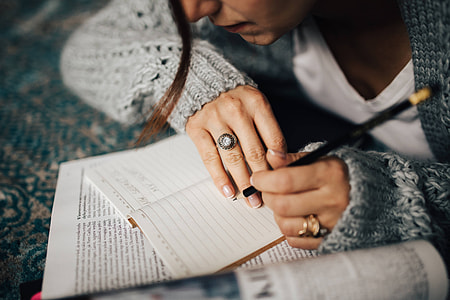 Woman in a grey sweater taking notes in an organizer
