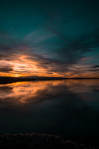 body of water under blue and orange sky during twilight