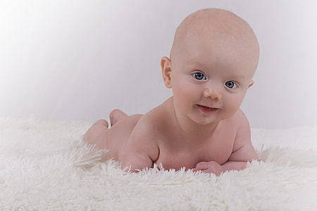 naked baby on top of white textile