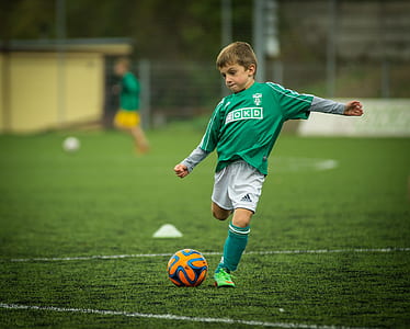 boy wearing green sweatshirt playing soccer
