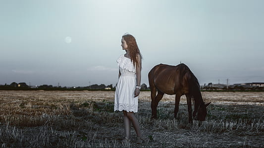 woman standing near brown horse
