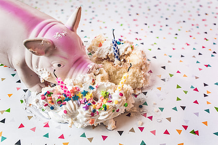 white and pink ceramic pig figurine near eaten cake