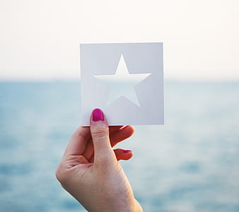 person holding white star paper cutout decor