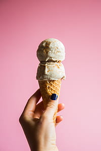 person holding a brown cown with ice cream