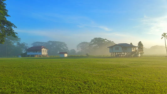 landscape photo of green grass field with two white wooden buildings