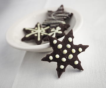 snowflake-shaped chocolate cookies on white ceramic saucer