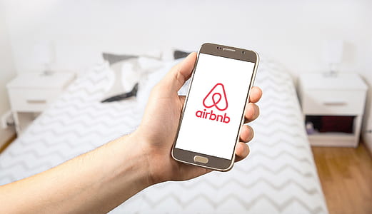 person holding smartphone displaying Airbnb logo