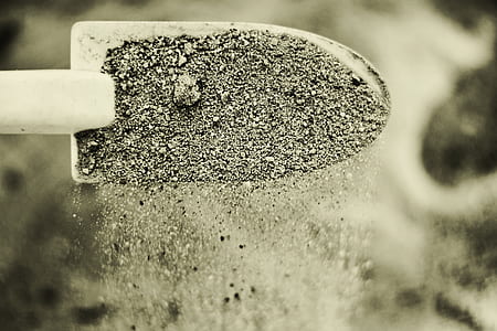 shovel with sand in close up photography