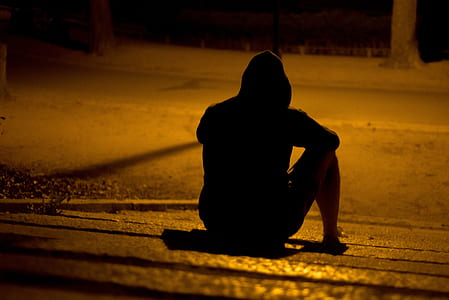 silhouette of person sitting on pathway during nighttime
