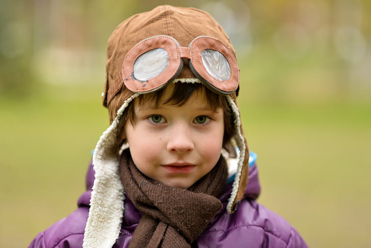 close-up photography of toddler wearing brown aviator cap and brown scarf