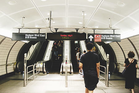 man wearing black t-shirt and black shorts outfit facing escalator