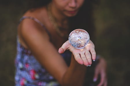 selective focus photo of woman holding clear water ball