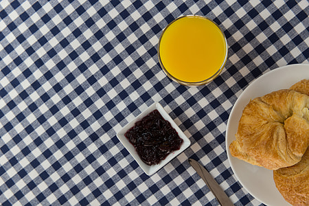 Overhead shot of orange juice drink, croissants and jam