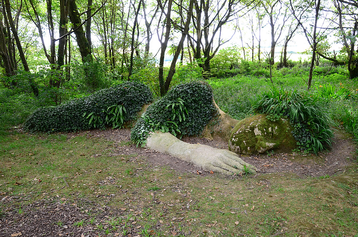 landscape photograph of reclining woman soil sculpture with green plants