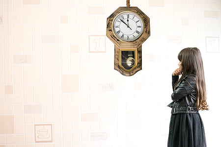 woman wearing black leather jacket standing near pendulum clock