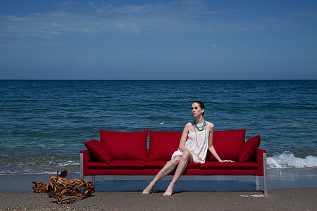 woman dressed and sitting on the sofa beside the seashore