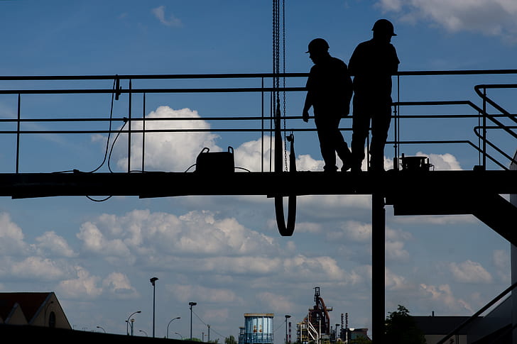 two linemen standing on bridge