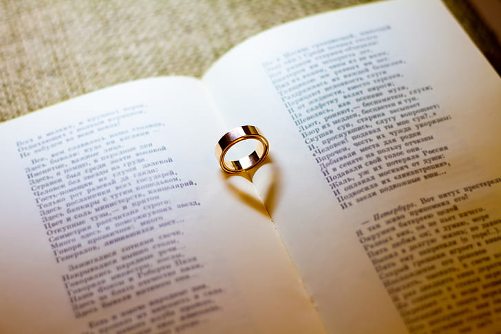 gold-colored wedding band on white book page