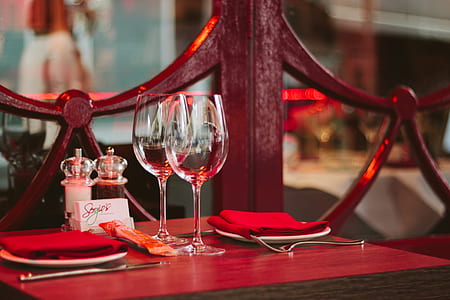 two clear wine glasses placed on red wooden table