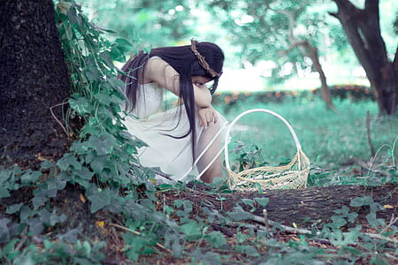 woman sitting near tree with basket