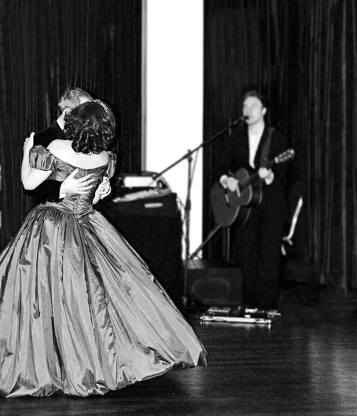 grayscale photo of man playing guitar while singing and man dancing with woman on floor