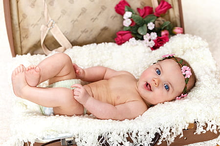 baby lying on white pad with floral crown headpiece