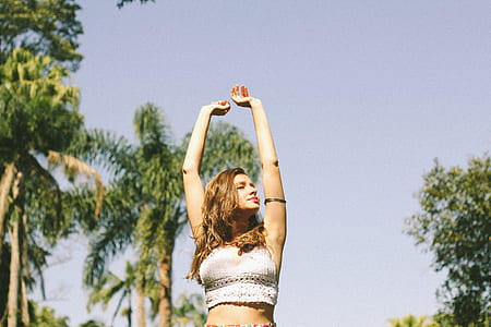 woman wearing white sleeveless crop top stretching her arms