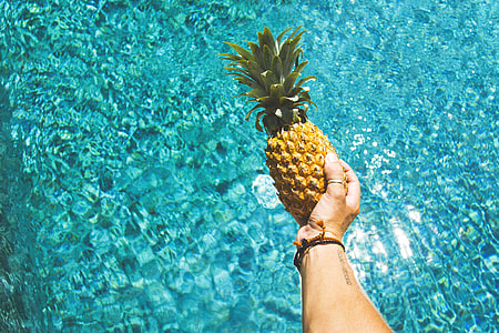 A man holding pineapple fruit over water
