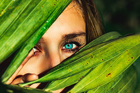 woman peeping in covered by palm leaves