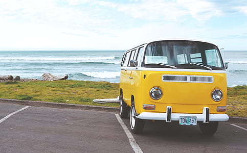 yellow and white bus parked near sea shore under cloudy sky