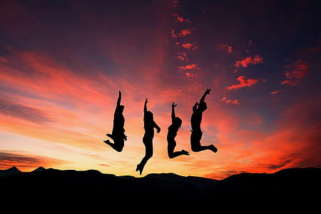 silhoutte photo of four people jumping during golden hour