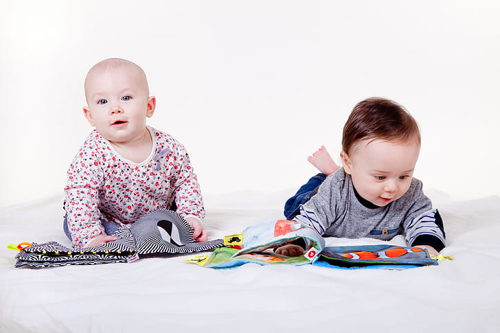 two baby crouching on white surface